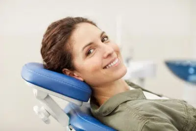 woman laying on dental chair smiling with teeth